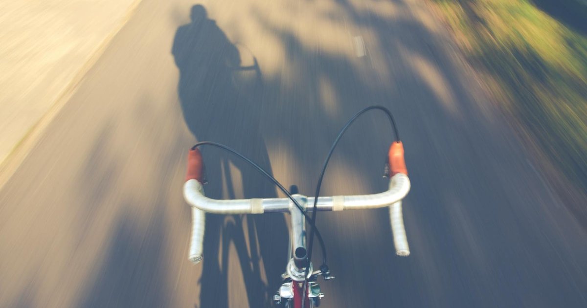 Cyclists riding along quiet Corfu country road between olive groves