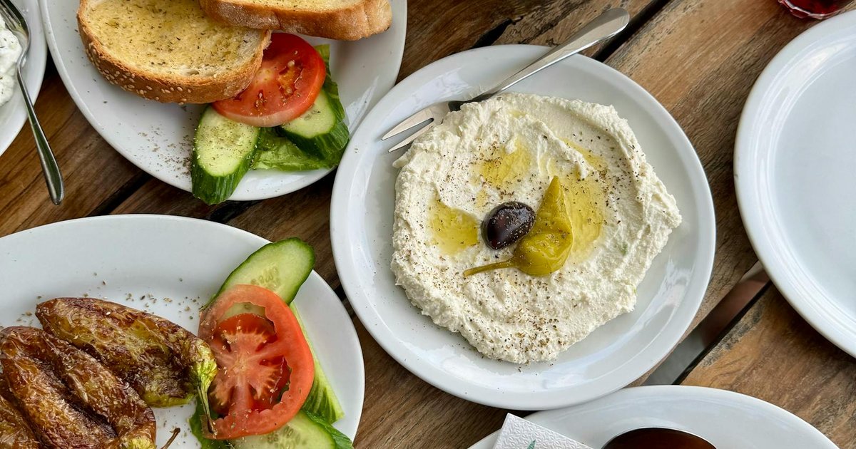 Traditional Corfu dishes including Pastitsada with bucatini and Greek salad on wooden table