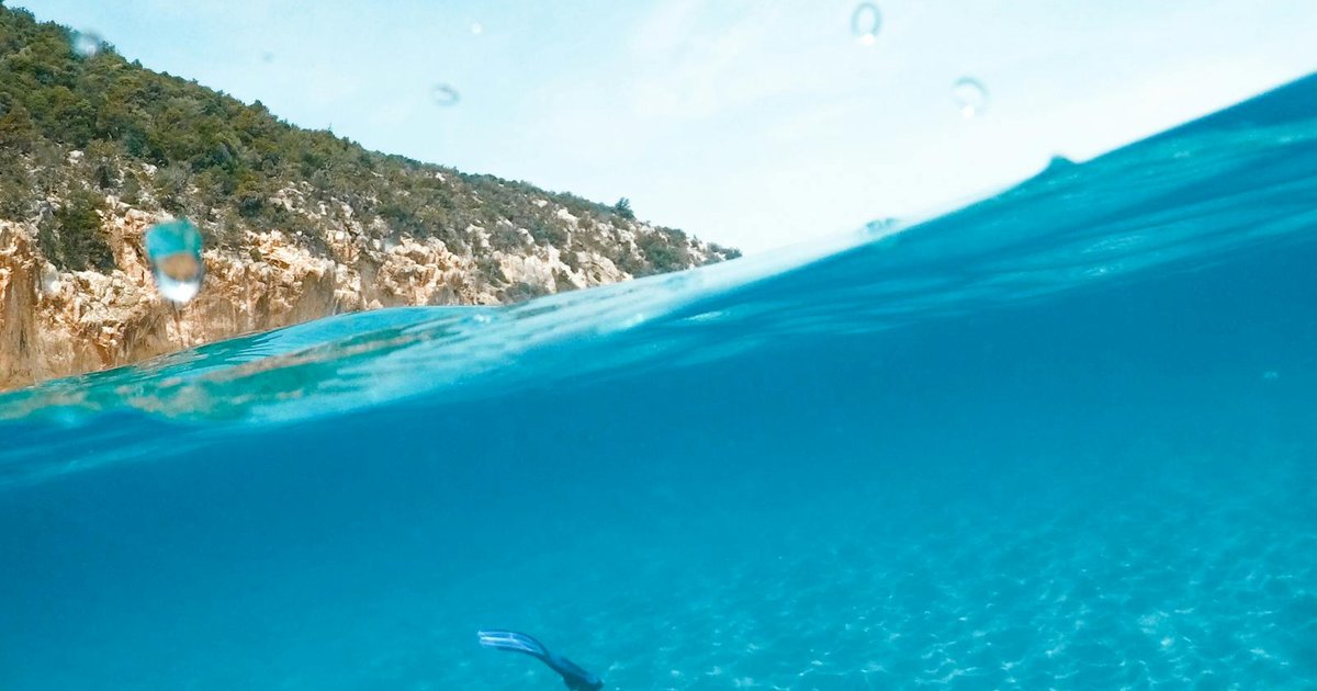 Snorkeler exploring the crystal-clear turquoise water of Corfu with rocky coastline