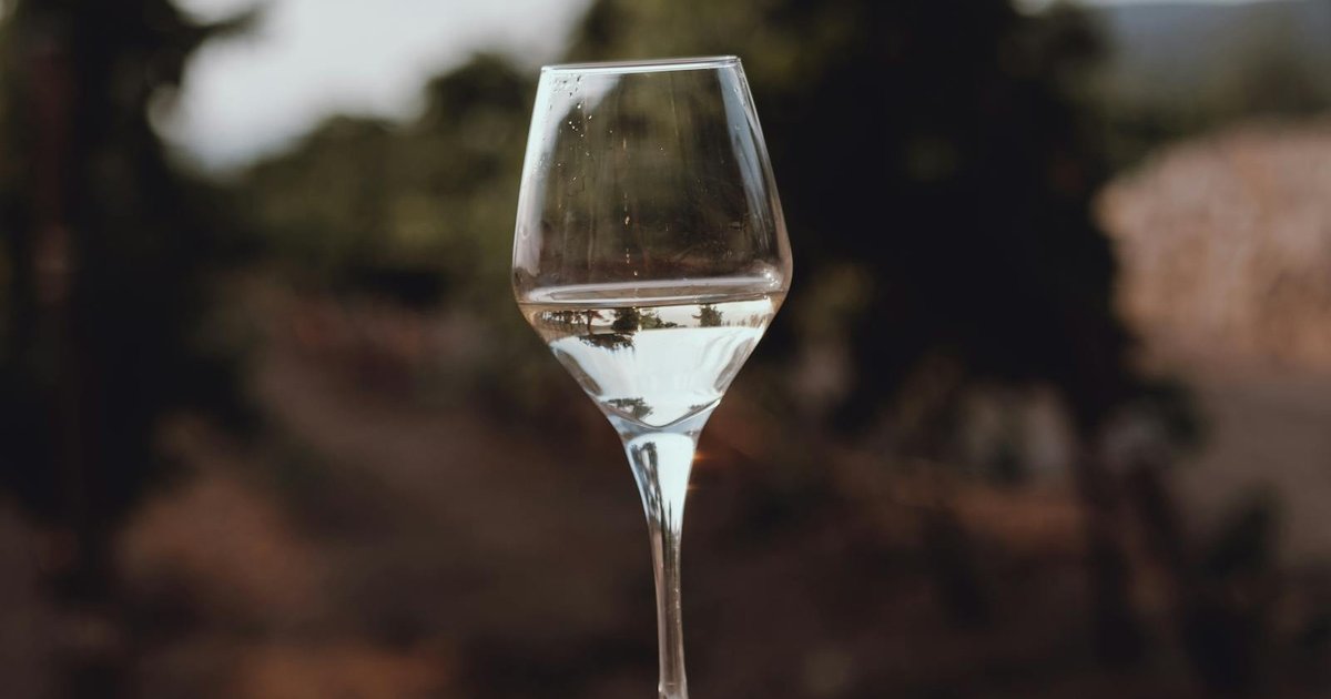 Glasses of Corfu wine on a wooden table with grapes and olives